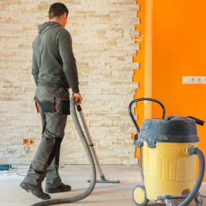 Ein Mitarbeiter saugt Baustaub nach der Sanierung auf