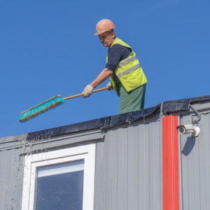 Ein Mitarbeiter reinigt Die Baucontainer an einer Baustelle