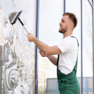 Eine Reinigungskraft erledigt die Glasreinigung von Schaufenstern