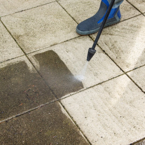 Ein stark verschmutzter Fliesenboden wird bei der Grundreinigung mit einem Hochdruckreiniger gesäubert