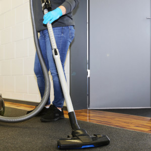 Eine Reinigungskraft mit Staubsauger
