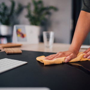Abwischen der Schreibtische während der Büroreinigung
