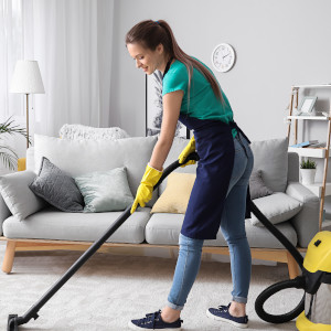Eine Reinigungskraft bei Staubsaugen einer Wohnung