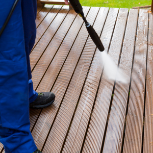 Eine Reinigungskraft arbeitet bei der Terrassenreinigung mit einem Hochdruckreiniger