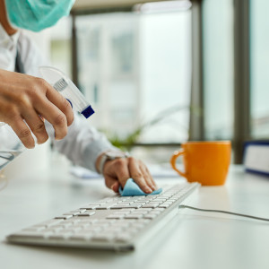 eine Mitarbeiterin reinigt Tastatur mit einem desinfizierenden Mittel
